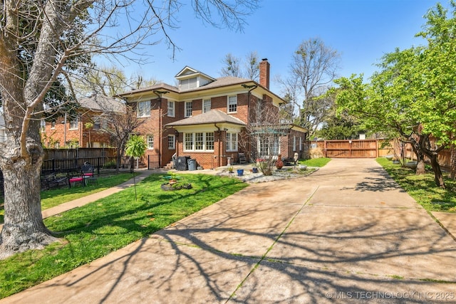 view of front of home featuring a front yard, brick siding, fence, and a chimney