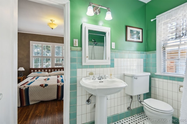 ensuite bathroom featuring toilet, a healthy amount of sunlight, ensuite bath, and tile walls