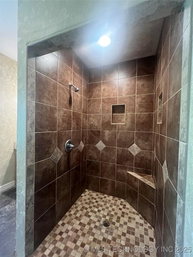220 Willow Ln, Hartshorne, OK 74547 - bathroom featuring tiled shower, a textured wall, and baseboards