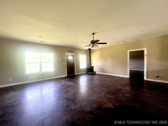 220 Willow Ln, Hartshorne, OK 74547 - unfurnished living room with a wood stove, concrete flooring, baseboards, and ceiling fan