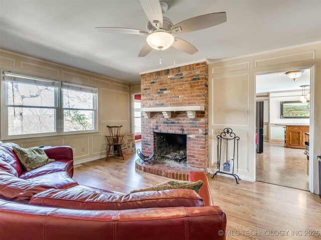 614 Oak Ridge Dr, Sand Springs, OK 74063 - living room featuring a decorative wall, a fireplace, light wood finished floors, ceiling fan, and ornamental molding