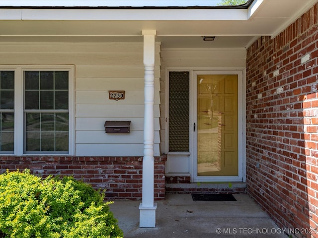 entrance to property with covered porch and brick siding
