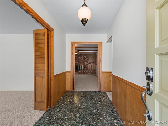 hall with wood walls, carpet flooring, and a wainscoted wall