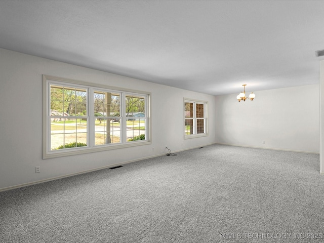 carpeted empty room featuring visible vents, a wealth of natural light, a notable chandelier, and baseboards