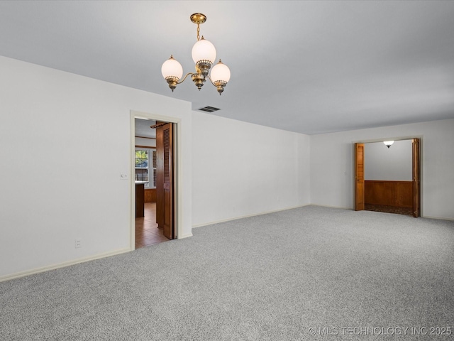 unfurnished room featuring baseboards, carpet flooring, a notable chandelier, and visible vents