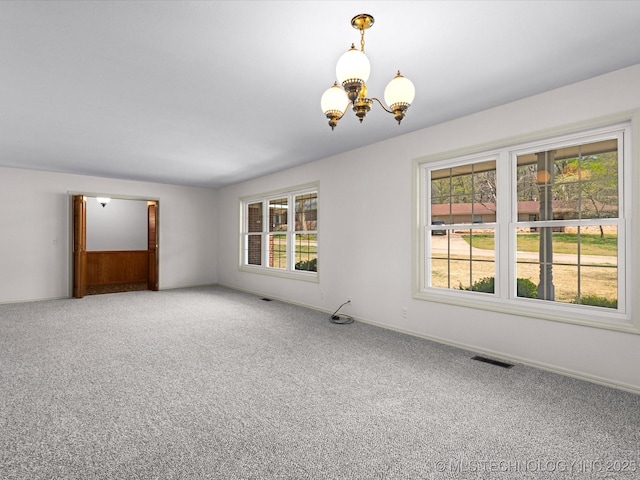 carpeted spare room featuring visible vents, baseboards, and a notable chandelier