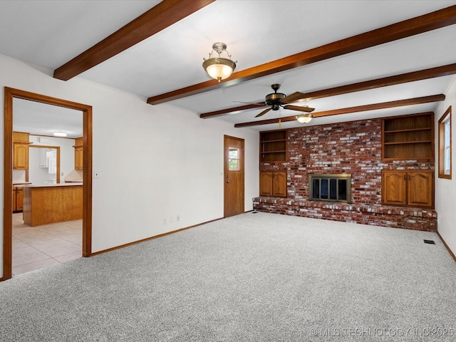unfurnished living room with built in features, baseboards, ceiling fan, beamed ceiling, and light carpet