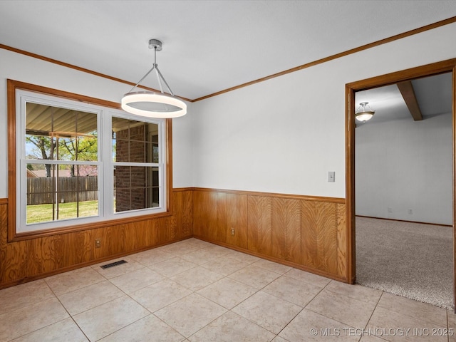 spare room with visible vents, wooden walls, crown molding, a wainscoted wall, and light tile patterned flooring