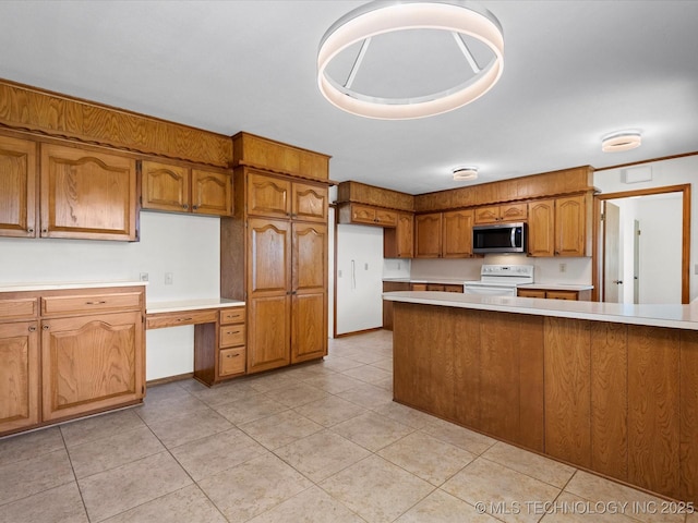 kitchen featuring light tile patterned floors, light countertops, white electric stove, brown cabinets, and stainless steel microwave