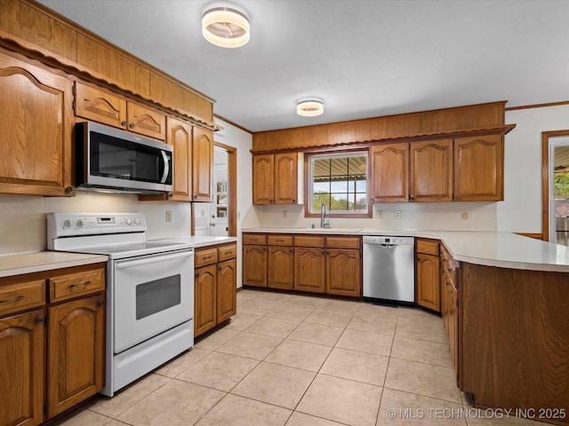 kitchen featuring crown molding, brown cabinetry, a peninsula, appliances with stainless steel finishes, and light countertops