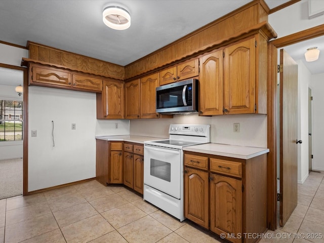 kitchen with electric range, brown cabinets, stainless steel microwave, and light countertops