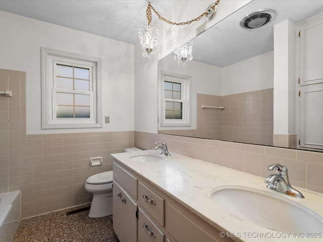 bathroom with a sink, visible vents, tile walls, and wainscoting