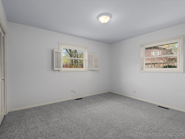 empty room featuring a healthy amount of sunlight, baseboards, carpet, and visible vents
