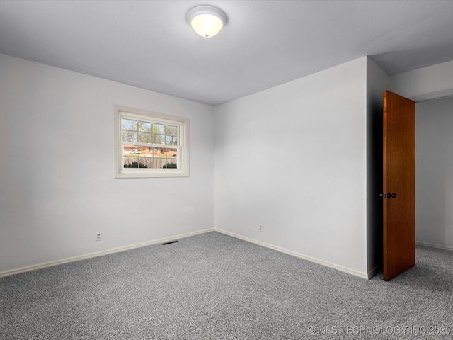 carpeted spare room featuring visible vents and baseboards
