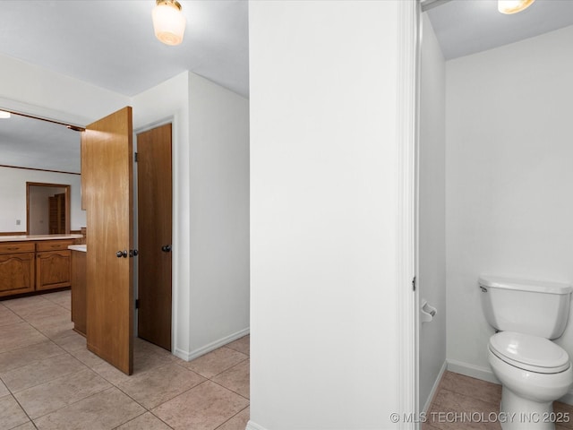 bathroom with toilet, tile patterned floors, and baseboards