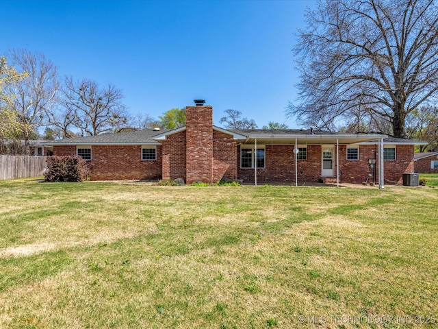 rear view of property featuring brick siding, central air condition unit, fence, and a lawn