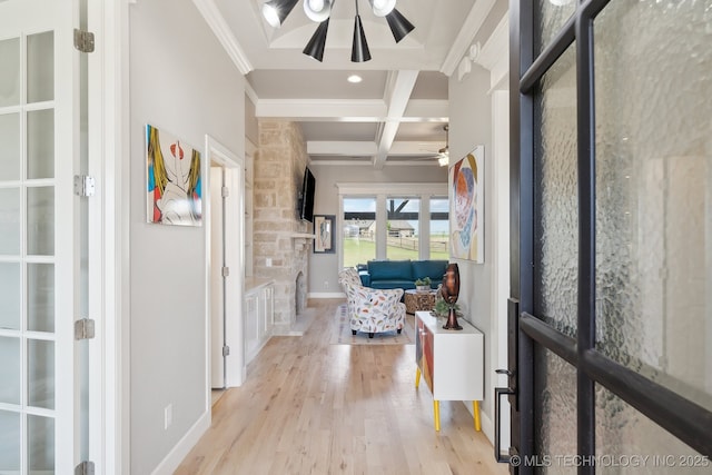 hall featuring baseboards, crown molding, beam ceiling, coffered ceiling, and light wood finished floors