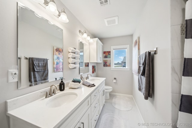 full bath with baseboards, double vanity, a sink, and visible vents