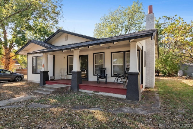 bungalow-style house featuring covered porch and a chimney