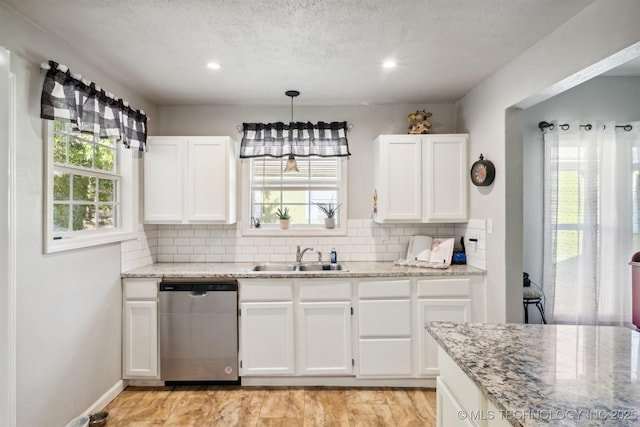 kitchen featuring tasteful backsplash, white cabinets, light stone counters, dishwasher, and a sink