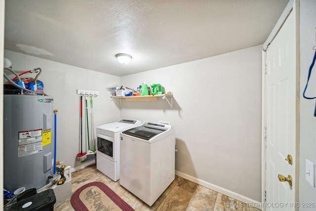 clothes washing area featuring laundry area, a textured ceiling, water heater, baseboards, and washing machine and dryer