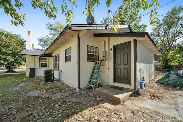 exterior space featuring central air condition unit, a chimney, and stucco siding