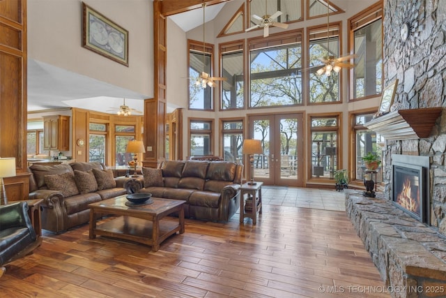 2667 Duguid Ln, Kingston, OK 73439 - living area featuring ceiling fan, high vaulted ceiling, wood-type flooring, a stone fireplace, and french doors