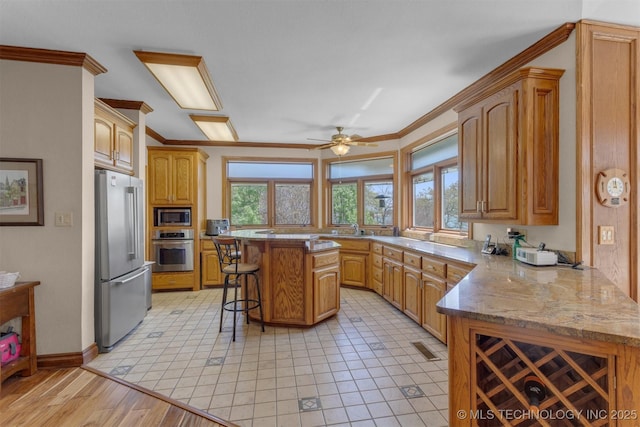 2667 Duguid Ln, Kingston, OK 73439 - kitchen with appliances with stainless steel finishes, a kitchen bar, crown molding, a sink, and a peninsula