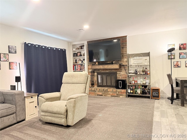 living room featuring built in features, visible vents, and a brick fireplace