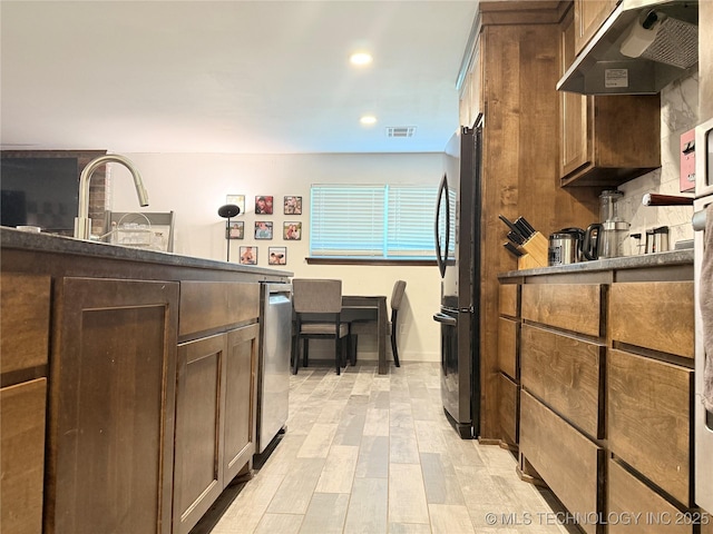 kitchen featuring freestanding refrigerator, visible vents, recessed lighting, under cabinet range hood, and dark countertops