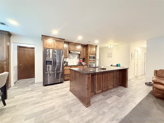 kitchen with dark stone counters, visible vents, under cabinet range hood, stainless steel appliances, and decorative backsplash