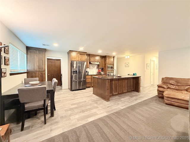 kitchen featuring recessed lighting, open floor plan, under cabinet range hood, and appliances with stainless steel finishes