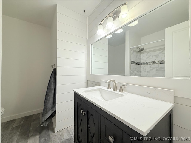 full bath featuring tiled shower, vanity, toilet, and wood finished floors
