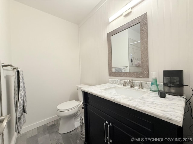 bathroom with toilet, wood finished floors, vanity, and baseboards