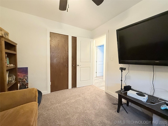 living area with a ceiling fan and carpet