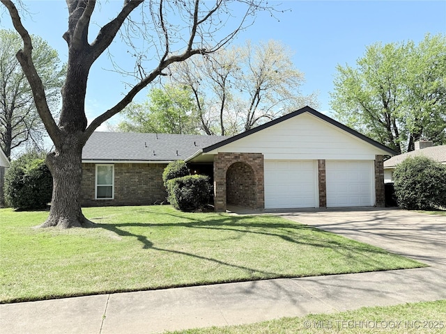 view of front of home featuring brick siding, a front yard, a garage, and concrete driveway