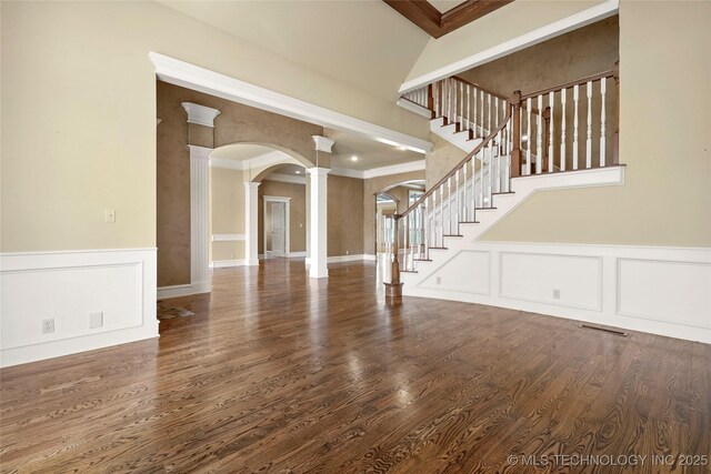 7505 S 4th St, Broken Arrow, OK 74011 - unfurnished living room with ornate columns, arched walkways, stairway, a decorative wall, and wood finished floors
