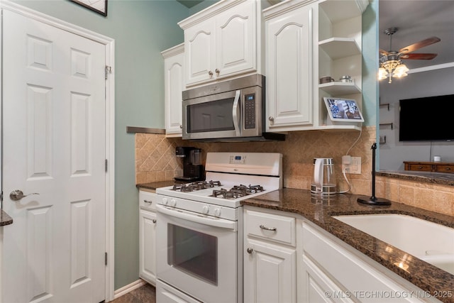 kitchen with stainless steel microwave, dark stone countertops, a ceiling fan, backsplash, and white range with gas stovetop