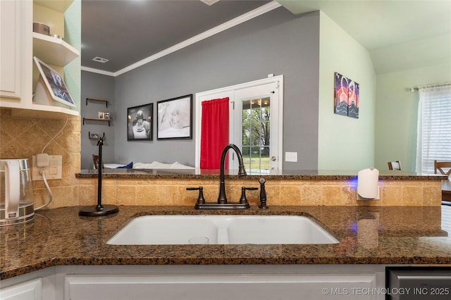 kitchen with open shelves, white cabinets, dark stone countertops, a sink, and backsplash