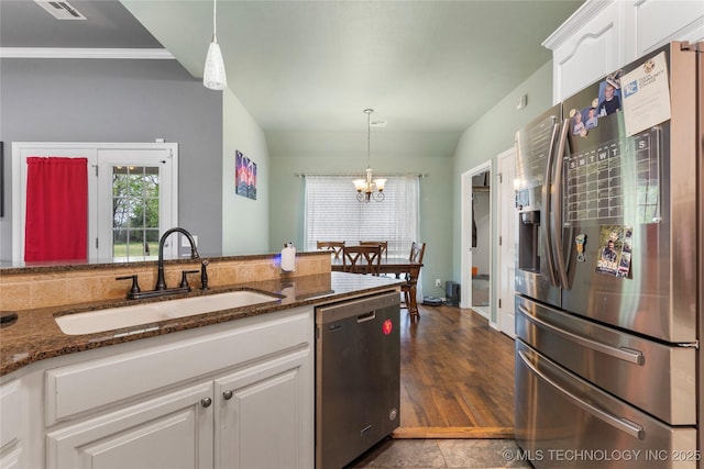 kitchen featuring dark stone counters, an inviting chandelier, white cabinetry, appliances with stainless steel finishes, and a sink