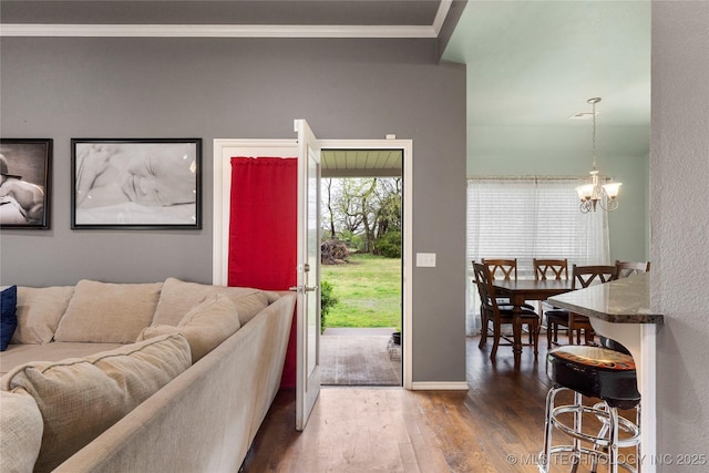 living room featuring crown molding, baseboards, an inviting chandelier, and wood finished floors