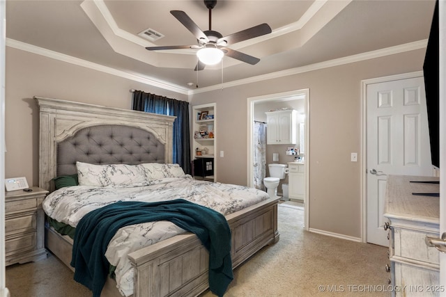 bedroom with ensuite bath, crown molding, visible vents, a raised ceiling, and light colored carpet