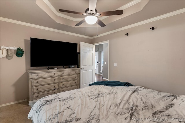 carpeted bedroom featuring baseboards, ornamental molding, a ceiling fan, and a raised ceiling