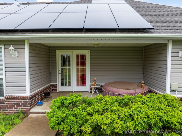 property entrance with roof with shingles and solar panels