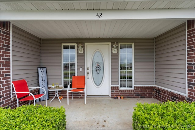 property entrance featuring brick siding and a porch