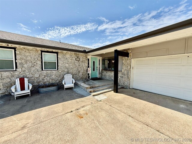 exterior space featuring concrete driveway, a garage, and stone siding