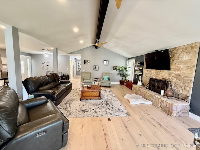living room featuring lofted ceiling with beams, a ceiling fan, a stone fireplace, wood-type flooring, and baseboards