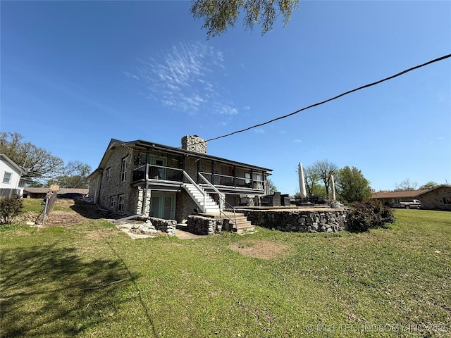 back of house featuring a chimney, a wooden deck, a yard, and stairs
