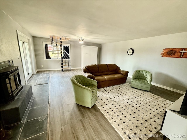 living area featuring a wood stove, baseboards, stairway, and dark wood-style floors