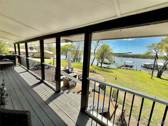 wooden terrace featuring a water view, a lawn, and a dock